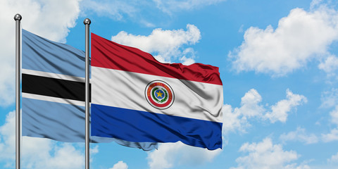Botswana and Paraguay flag waving in the wind against white cloudy blue sky together. Diplomacy concept, international relations.