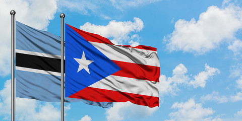 Botswana and Puerto Rico flag waving in the wind against white cloudy blue sky together. Diplomacy concept, international relations.