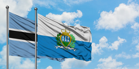 Botswana and San Marino flag waving in the wind against white cloudy blue sky together. Diplomacy concept, international relations.
