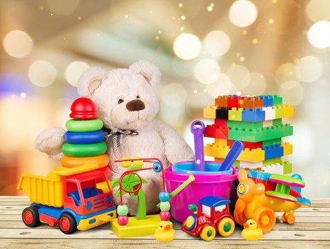 Bear and colorful toys on a wooden desk on abstract light background