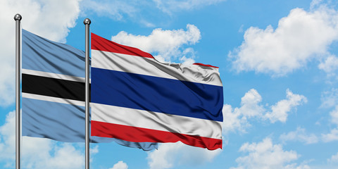 Botswana and Thailand flag waving in the wind against white cloudy blue sky together. Diplomacy concept, international relations.