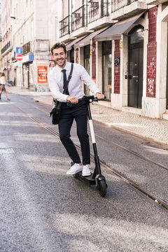 Happy young businessman riding e-scooter in the city, Lissabon, Portugal