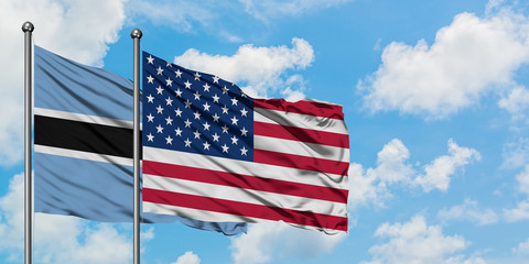 Botswana and United States flag waving in the wind against white cloudy blue sky together. Diplomacy concept, international relations.