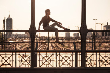 Young woman sitting on Hacker bridge at sunset, Munich, Germany