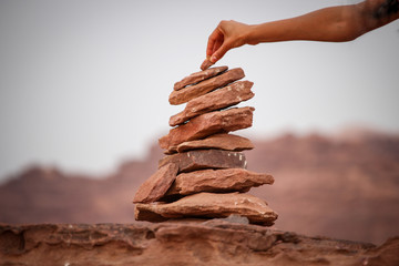 Adding a rock to a stone cairn in the desert of Wadi Ru, Jordan