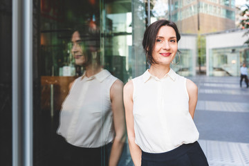 Portrait of confident young businesswoman reflected in glass front, Berlin, Germany