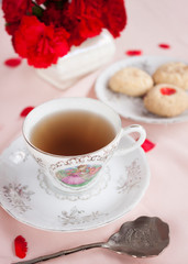 Obraz na płótnie Canvas tea time with red flowers and dessert
