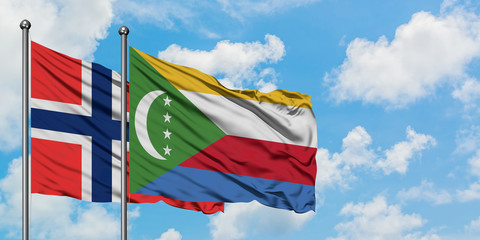 Bouvet Islands and Comoros flag waving in the wind against white cloudy blue sky together. Diplomacy concept, international relations.
