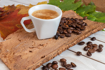 Cup and grain of coffee over different color autumn leave