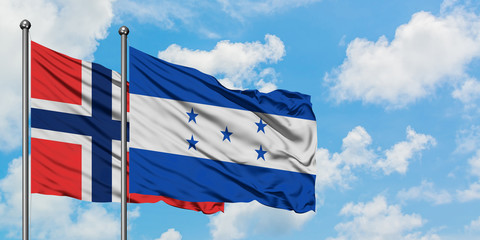 Bouvet Islands and Honduras flag waving in the wind against white cloudy blue sky together. Diplomacy concept, international relations.