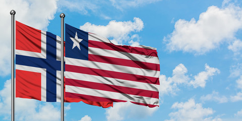 Bouvet Islands and Liberia flag waving in the wind against white cloudy blue sky together. Diplomacy concept, international relations.