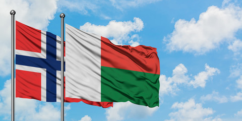 Bouvet Islands and Madagascar flag waving in the wind against white cloudy blue sky together. Diplomacy concept, international relations.