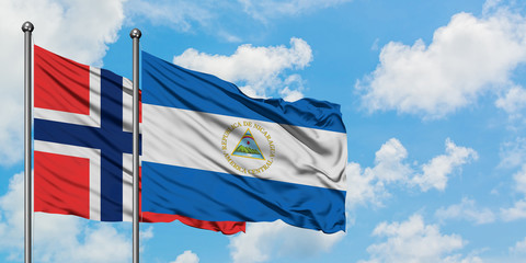 Bouvet Islands and Nicaragua flag waving in the wind against white cloudy blue sky together. Diplomacy concept, international relations.