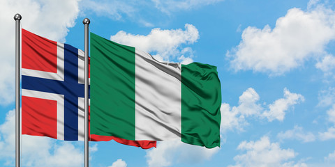 Bouvet Islands and Nigeria flag waving in the wind against white cloudy blue sky together. Diplomacy concept, international relations.
