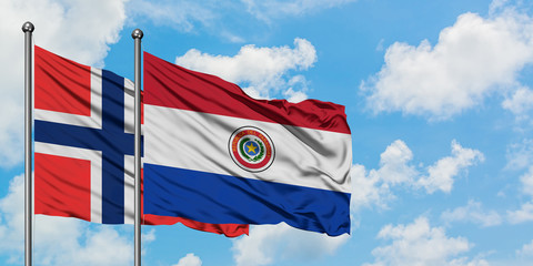 Bouvet Islands and Paraguay flag waving in the wind against white cloudy blue sky together. Diplomacy concept, international relations.