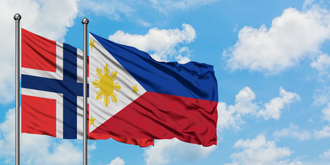 Bouvet Islands and Philippines flag waving in the wind against white cloudy blue sky together. Diplomacy concept, international relations.