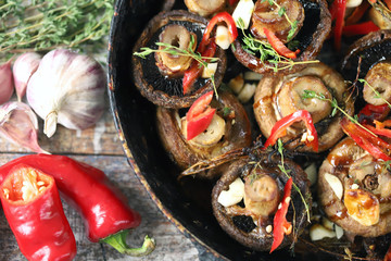Large champignons baked in a pan with thyme, garlic and chili. Healthy vegan lunch. Keto diet. Selective focus. Macro.