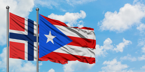 Bouvet Islands and Puerto Rico flag waving in the wind against white cloudy blue sky together. Diplomacy concept, international relations.
