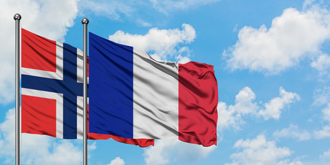 Bouvet Islands and Reunion flag waving in the wind against white cloudy blue sky together. Diplomacy concept, international relations.