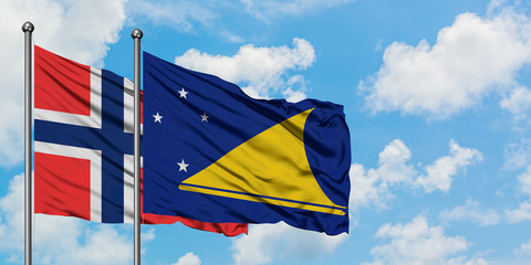 Bouvet Islands and Tokelau flag waving in the wind against white cloudy blue sky together. Diplomacy concept, international relations.