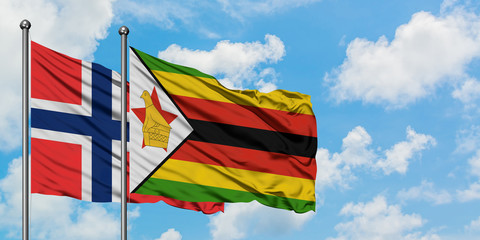 Bouvet Islands and Zimbabwe flag waving in the wind against white cloudy blue sky together. Diplomacy concept, international relations.