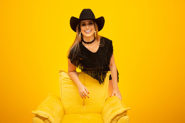 Happy sexy cowgirl on yellow background