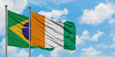 Brazil and Cote D'Ivoire flag waving in the wind against white cloudy blue sky together. Diplomacy concept, international relations.