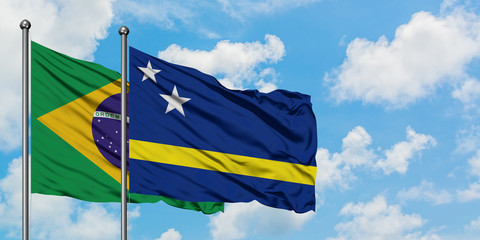Brazil and Curacao flag waving in the wind against white cloudy blue sky together. Diplomacy concept, international relations.