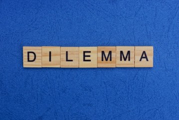 word dilemma made of wooden letters on a blue table