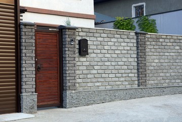 red wooden door and gray brick fence on a rural street