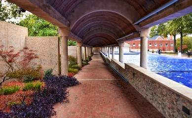 Covered brick walkway bordered with landscaping and large reflecting pool