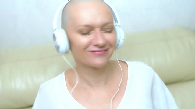 close-up. a bald woman in headphones listens to music and moves her head to the beat of the music.