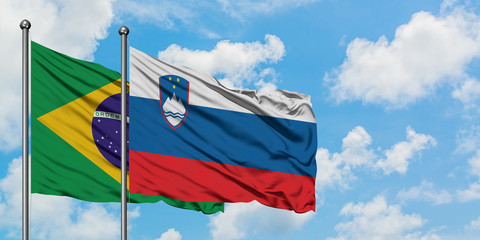 Brazil and Slovenia flag waving in the wind against white cloudy blue sky together. Diplomacy concept, international relations.