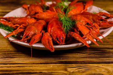 Plate with boiled crayfishes on wooden table