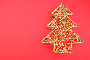 Openwork metal Christmas tree on a red background. Element of Christmas and New year decor. Close...