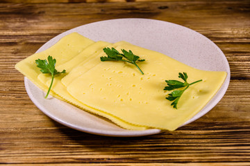 Sliced cheese and parsley in ceramic plate on wooden table