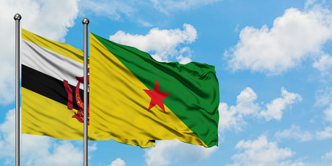 Brunei and French Guiana flag waving in the wind against white cloudy blue sky together. Diplomacy concept, international relations.