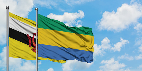 Brunei and Gabon flag waving in the wind against white cloudy blue sky together. Diplomacy concept, international relations.