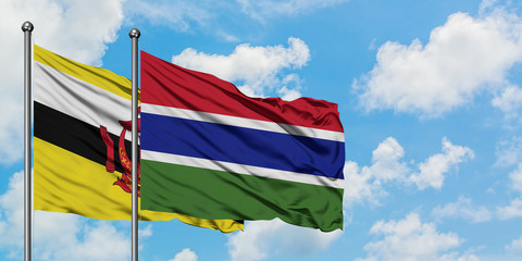 Brunei and Gambia flag waving in the wind against white cloudy blue sky together. Diplomacy concept, international relations.