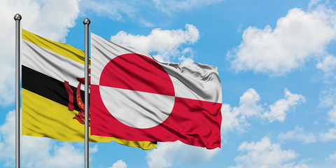 Brunei and Greenland flag waving in the wind against white cloudy blue sky together. Diplomacy concept, international relations.
