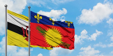 Brunei and Guadeloupe flag waving in the wind against white cloudy blue sky together. Diplomacy concept, international relations.