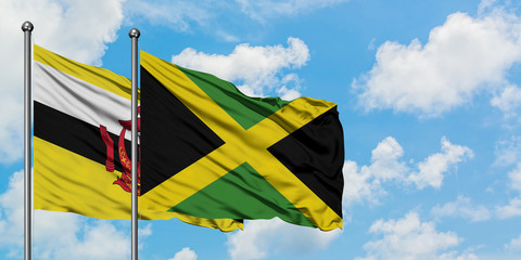 Brunei and Jamaica flag waving in the wind against white cloudy blue sky together. Diplomacy concept, international relations.
