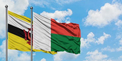 Brunei and Madagascar flag waving in the wind against white cloudy blue sky together. Diplomacy concept, international relations.