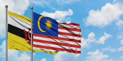 Brunei and Malaysia flag waving in the wind against white cloudy blue sky together. Diplomacy concept, international relations.
