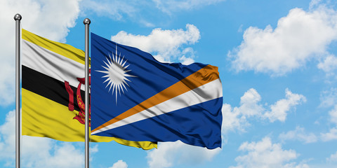 Brunei and Marshall Islands flag waving in the wind against white cloudy blue sky together. Diplomacy concept, international relations.