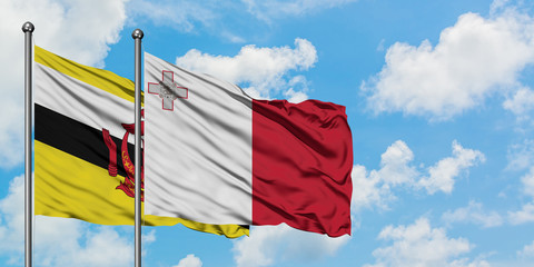 Brunei and Malta flag waving in the wind against white cloudy blue sky together. Diplomacy concept, international relations.
