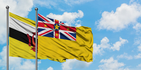 Brunei and Niue flag waving in the wind against white cloudy blue sky together. Diplomacy concept, international relations.
