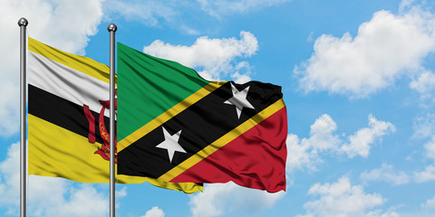 Brunei and Saint Kitts And Nevis flag waving in the wind against white cloudy blue sky together. Diplomacy concept, international relations.