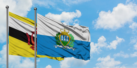 Brunei and San Marino flag waving in the wind against white cloudy blue sky together. Diplomacy concept, international relations.