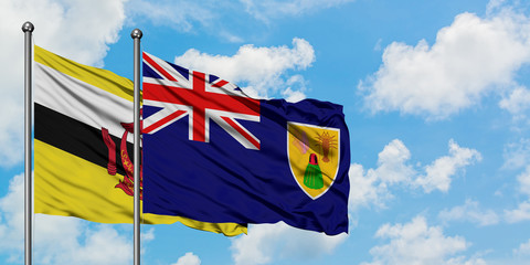 Brunei and Turks And Caicos Islands flag waving in the wind against white cloudy blue sky together. Diplomacy concept, international relations.